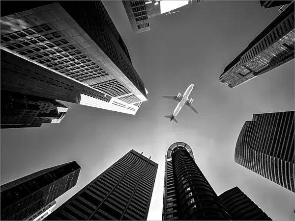 Tall city buildings and a plane flying overhead