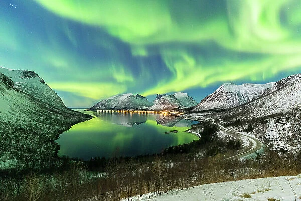 The aurora borealis lights up in the sky and is reflected in the fjord. Northern Norway, Europe