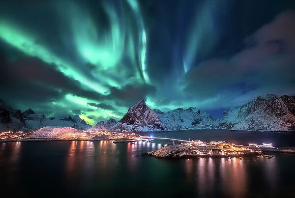 Aurora borealis. Lofoten islands, Norway. Aurora. Green northern lights. Starry sky with polar lights. Night winter landscape with aurora, sea with sky reflection and snowy mountains