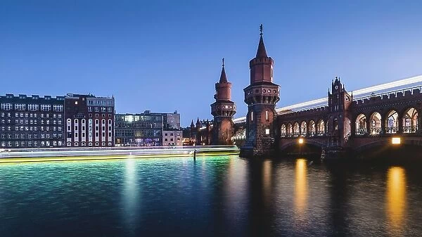 Berlin Oberbaum Bridge with traces of light from ship and train in the evening, Berlin, Germany