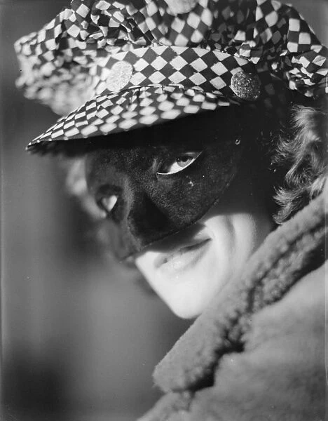 Face Mask. circa 1930: A woman conceals her identity at a masked ball