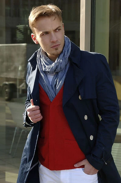 Fashion image, young man wearing a blue coat and a red sweater