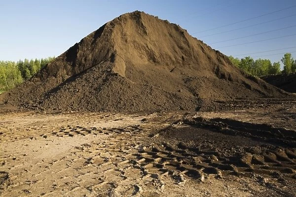 Heavy tire tracks and a mound of topsoil in a commercial sandpit, Quebec, Canada