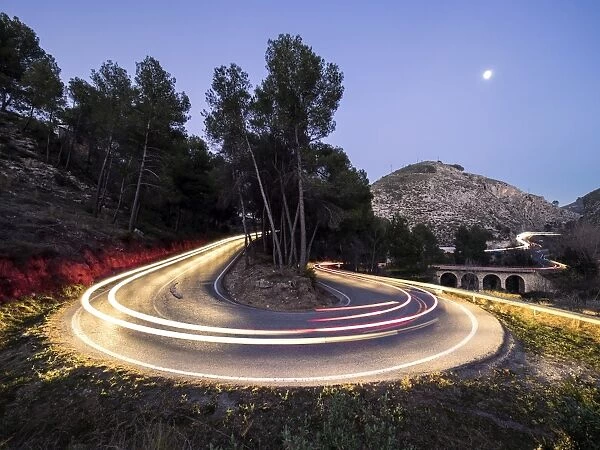 Lights of vehicles in movement circulating along a carretera with curves very closed in the moonlight