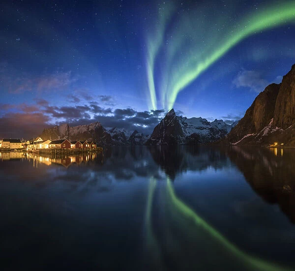 Northern lights over fishing village with mountain range on coastline at Hamnoy