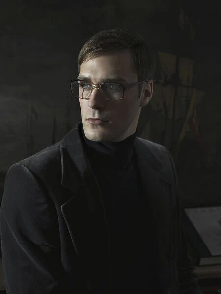 Student wearing a suit and glasses, sitting in front of a painting