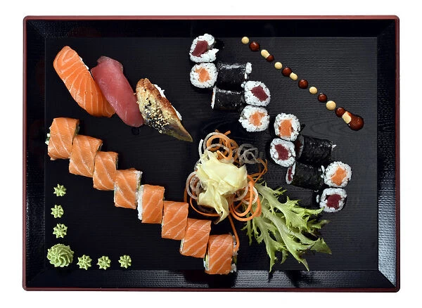 Sushi dish with Maki, Uramaki, Nigiri with salmon, tuna, eel, fresh ginger, wasabi, on a Japanese wooden plate