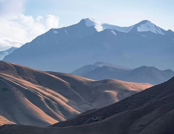 View over eroded mountainous landscape with brown hills, high mountains with snow in the back, Konorchek Canyon, Chuy, Kyrgyzstan