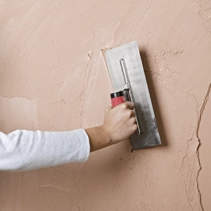 Applying a second layer of plaster to a wall using trowel