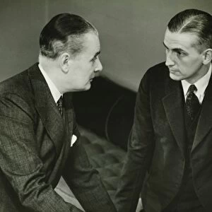 Two businessmen leaning on desk, talking, (B&W)