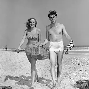 Couple walking with picnic basket on beach