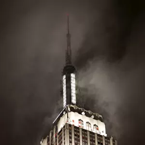 Top of Empire State Building in clouds at nght