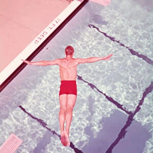Man diving into swimming pool, overhead view. (Photo by H