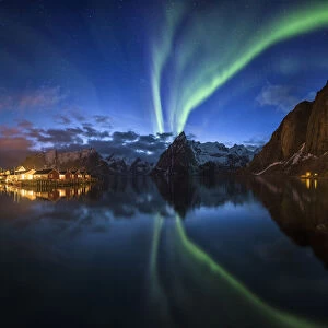 Northern lights over fishing village with mountain range on coastline at Hamnoy