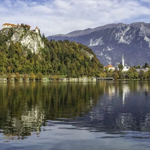 Reflection of Bled Castle overlook Lake Bled, surrounded with high mountains of the