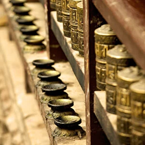 A row of prayer mills and butter lamps in the Golden Temple, a Buddhist temple, Patan, Nepal, Asia