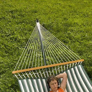 Senior woman with netbook and headset lying in a hammock