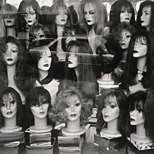 Window display of mannequin heads wearing assorted wigs