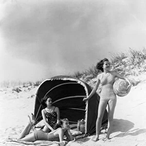 Three Women On Beach Two Are Under Canvas Sun Wind Screen With Fringe Other Is Standing