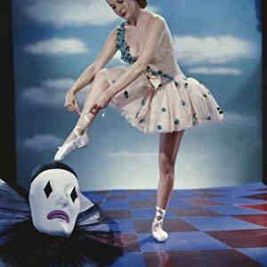 Young ballet dancer tying ballet slippers