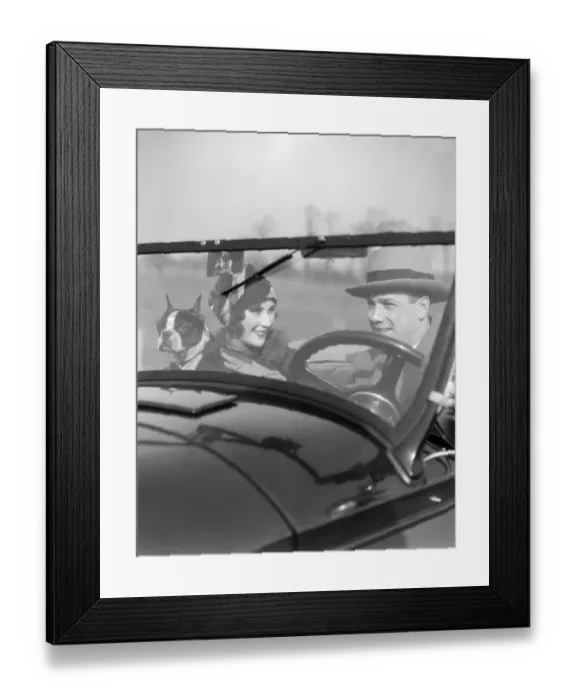 Framed Print : Smiling Couple With Dog Boston Terrier In Front Seat Of Convertible View Through The Windshield Into The Car Man At Steering Wheel Fashion Hats