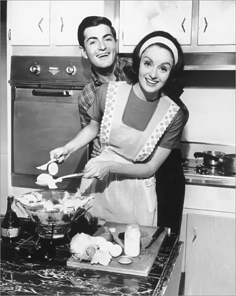 Couple standing in kitchen, smiling, (B&W)