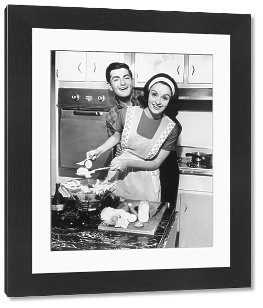 Couple standing in kitchen, smiling, (B&W)