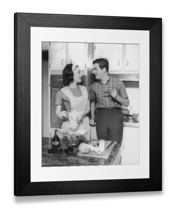 Framed Print : Couple standing in kitchen, smiling, (B&W)