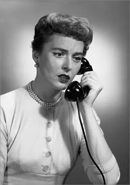 Woman talking on phone in studio, (B&W)