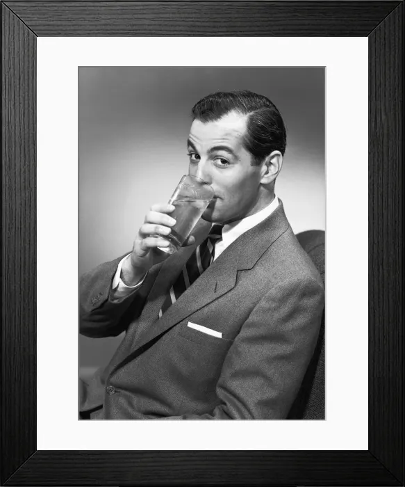 Framed Print : Man drinking water from glass, posing in studio, (B&W), portrait Framed Print : Man drinking water from glass, posing in studio, (B&W), portrait