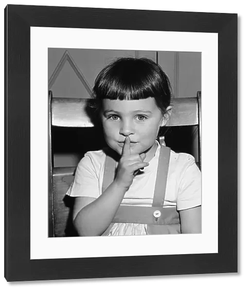 Girl (4-5) holding finer on mouth, (B&W), portrait