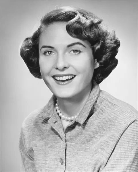 Smiling woman posing in studio, (B&W), portrait