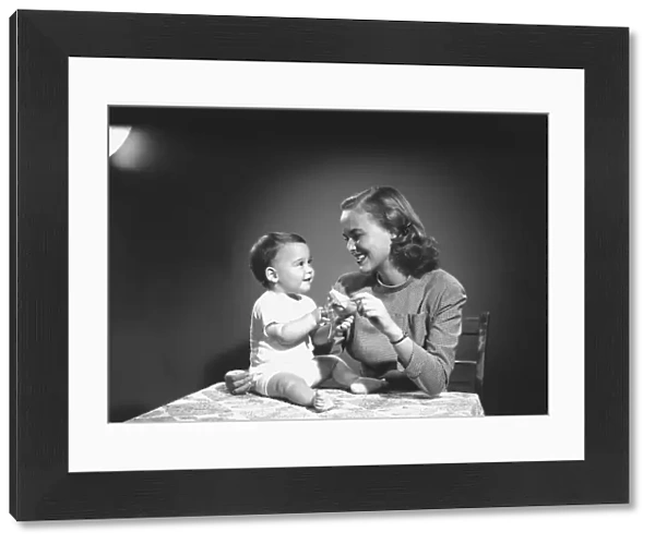 Mother with baby (6-9 months) playing at home, (B&W)
