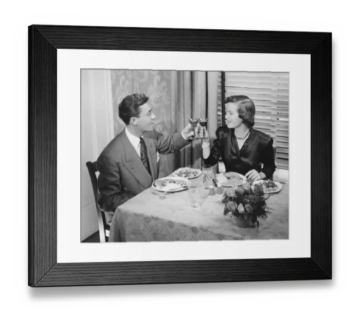 Framed Print : Couple toasting at dinner table, (B&W), elevated view Framed Print : Couple toasting at dinner table, (B&W), elevated view