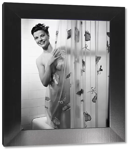 Woman peering through shower curtain, (B&W), portrait