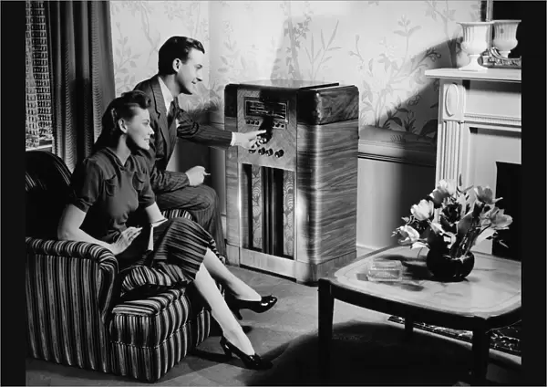 Couple listening to radio in living room, (B&W)