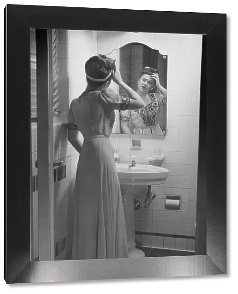 Woman suffering headache standing in front of bathroom mirror, (B&W)