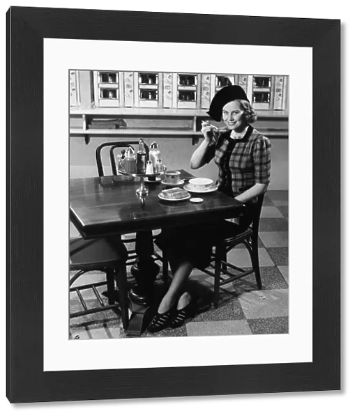 Woman in fancy hat eating breakfast in bar, (B&W), portrait