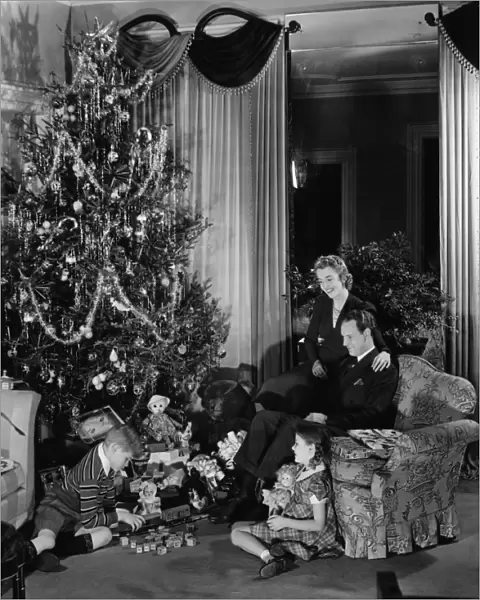 Family with two children (6-9) sitting at Christmas tree, (B&W)