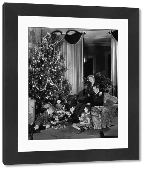 Family with two children (6-9) sitting at Christmas tree, (B&W)