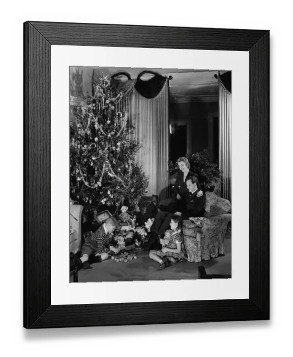 Framed Print : Family with two children (6-9) sitting at Christmas tree, (B&W) Framed Print : Family with two children (6-9) sitting at Christmas tree, (B&W)