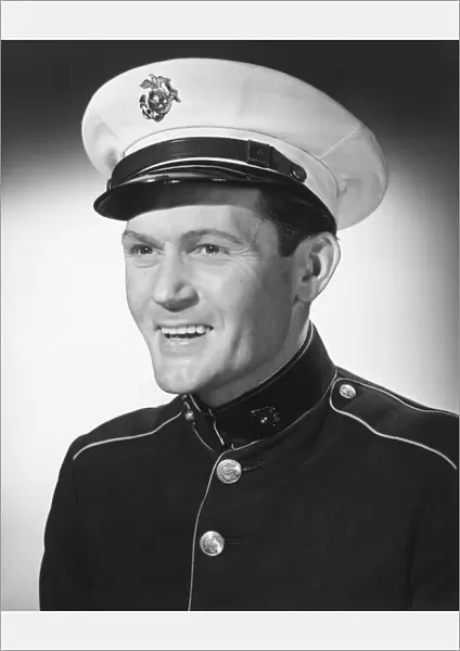 Smiling man in military uniform posing in studio, (B&W), portrait