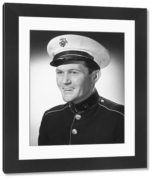 Smiling man in military uniform posing in studio, (B&W), portrait