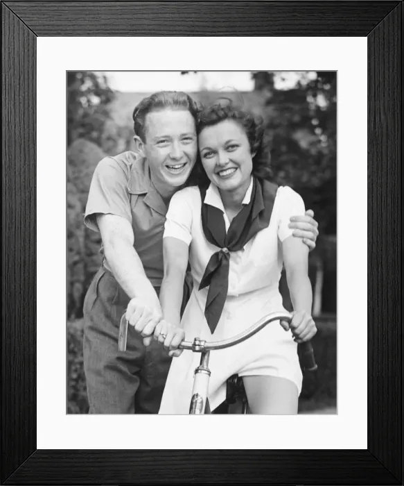 Framed Print : Man embracing woman sitting on bike, (B&W), portrait