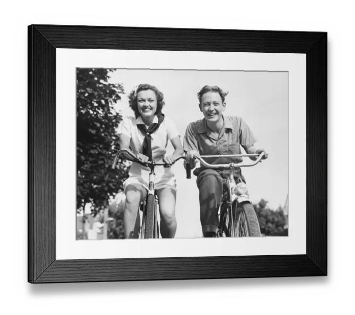 Framed Print : Man and woman riding bikes, (B&W), low angle view Framed Print : Man and woman riding bikes, (B&W), low angle view