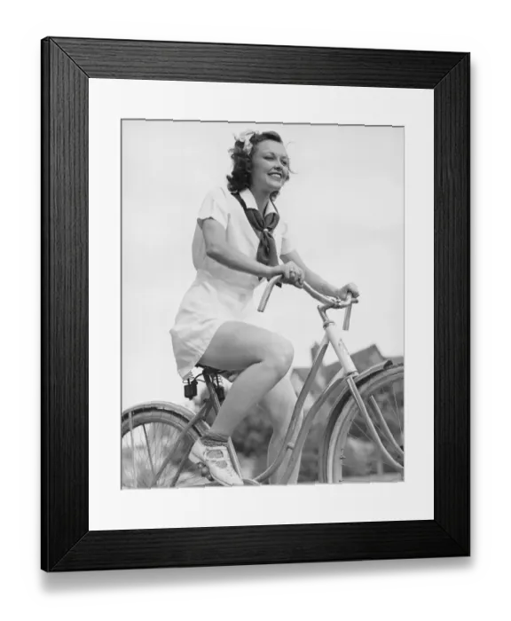 Framed Print : Young woman riding bicycle, (B&W), low angle view