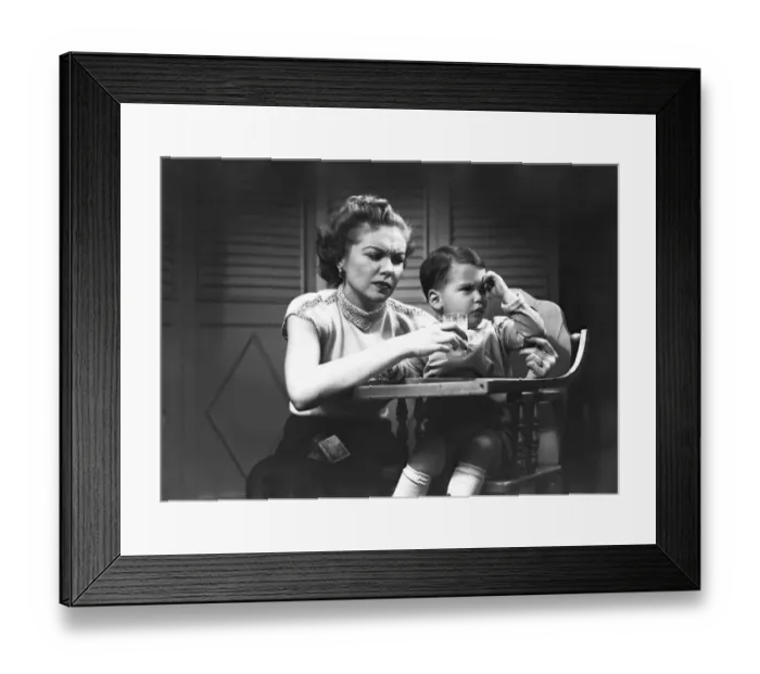 Framed Print : Mother giving glass of milk to son (2-3) sitting in high chair, (B&W) Framed Print : Mother giving glass of milk to son (2-3) sitting in high chair, (B&W)
