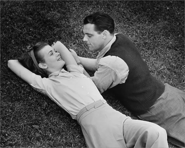 Romantic couple lying on grass, (B&W), elevated view