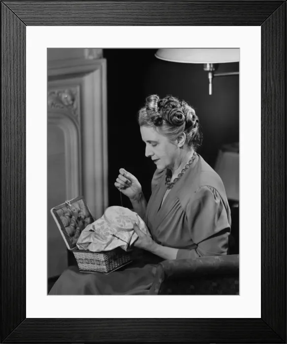 Framed Print : Mature woman sitting in living room, doing needlepoint, (B&W) Framed Print : Mature woman sitting in living room, doing needlepoint, (B&W)