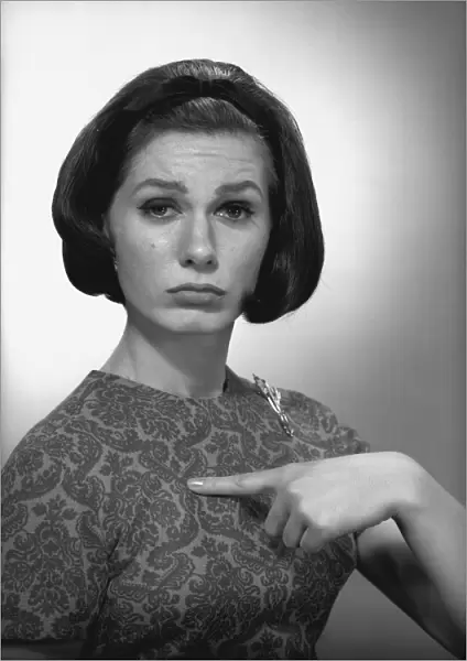 Woman pointing on herself in studio, (B&W), portrait